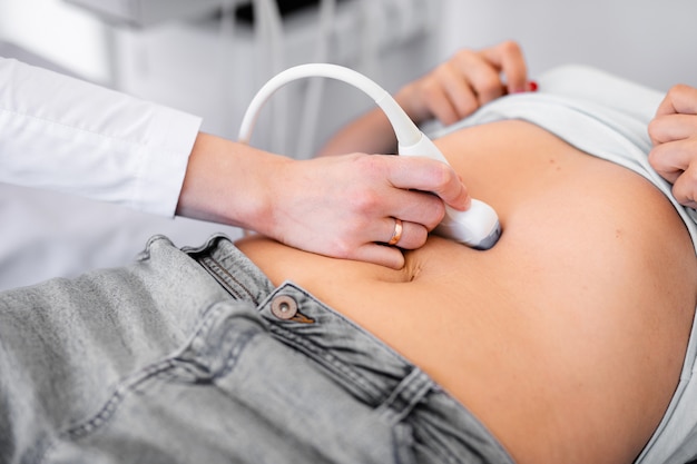 Ultrasound sensor of modern ultrasonic scanner in young woman doctor's hands and a patient in clinic