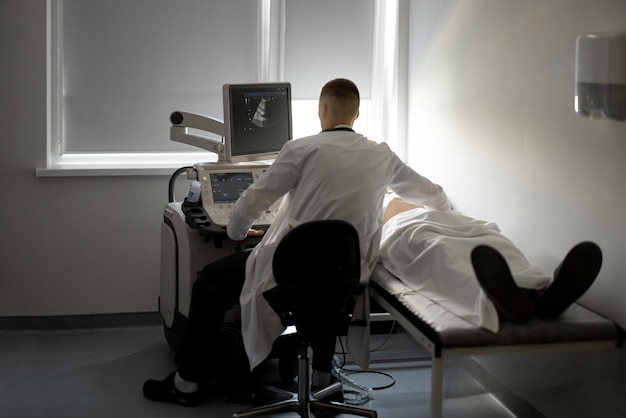 Ultrasound specialist examining male patient in medical office