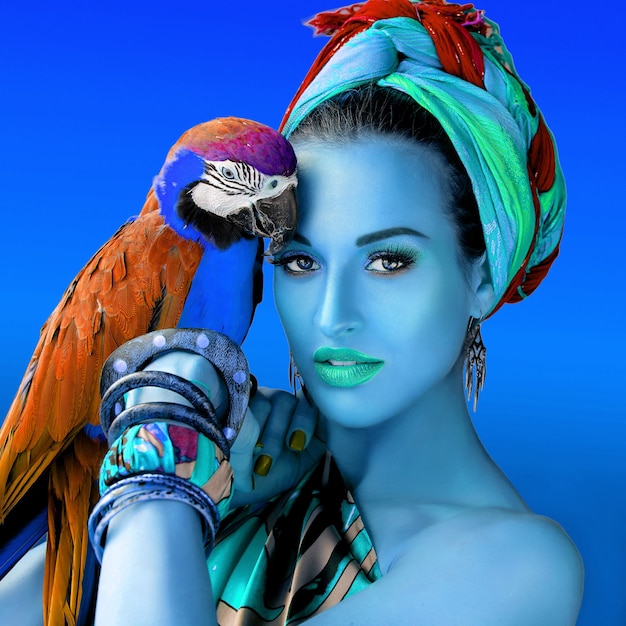 Ultraviolet portrait of young attractive woman in african style holding ara parrot on her hand  