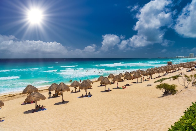 멕시코 칸쿤 근처의 화창한 날 푸른 물이 있는 모래 해변의 우산