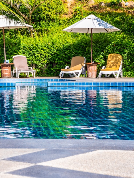 Umbrella and chair around luxury outdoor swimming pool