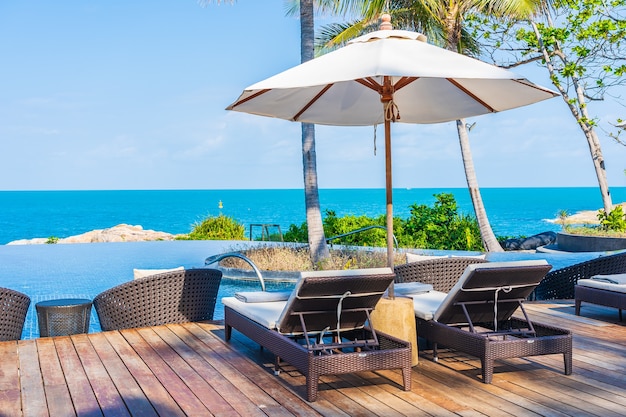 Umbrella and chair around outdoor swimming pool in hotel resort with sea ocean view for travel vacation