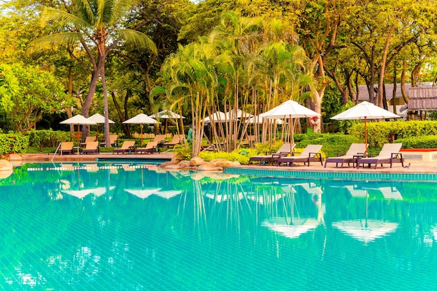 Foto ombrellone e sedia intorno alla piscina in hotel resort per viaggi di piacere e vacanze vicino alla spiaggia dell'oceano al tramonto o all'alba