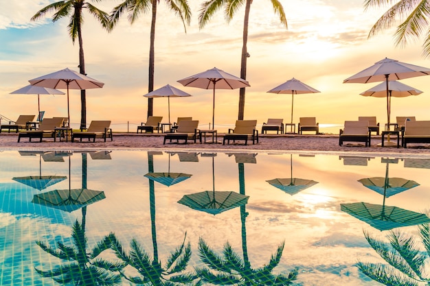 Umbrella and chair around swimming pool in resort hotel for leisure travel and vacation neary sea ocean beach