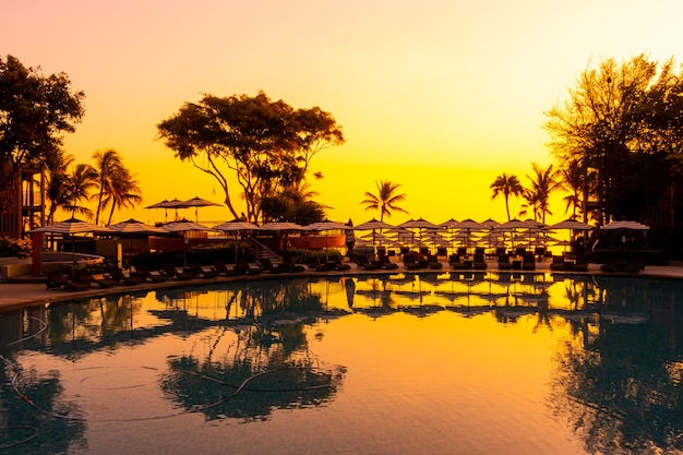 Umbrella and chair sofa around outdoor swimming pool in hotel resort for travel holiday vacation