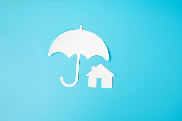 傘カバー青い背景のホームペーパー保証メンテナンス不動産と保険のコンセプト