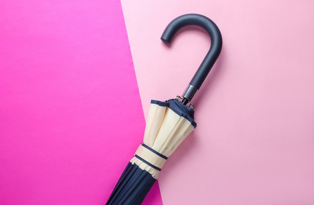 Photo umbrella handle on duotone pink surface top view, minimalism