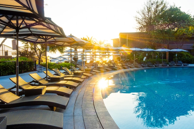 여행 휴가 휴가를위한 호텔 리조트의 야외 수영장 주변의 우산과 수영장 침대