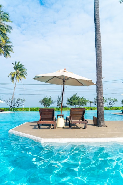 umbrella with bed pool around swimming pool with ocean sea background - holiday and vacation concept