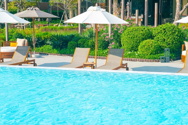 umbrella with bed pool around swimming pool with ocean sea background - holiday and vacation concept