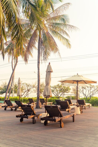 umbrella with bed pool around swimming pool with ocean sea background - holiday and vacation concept