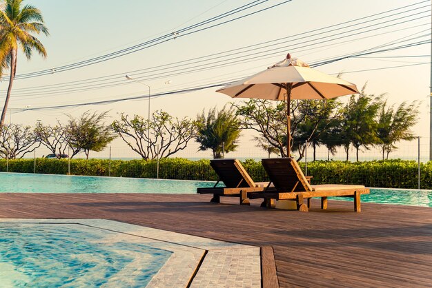 umbrella with bed pool around swimming pool with ocean sea background - holiday and vacation concept