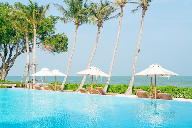 umbrella with bed pool around swimming pool with ocean sea background - holiday and vacation concept