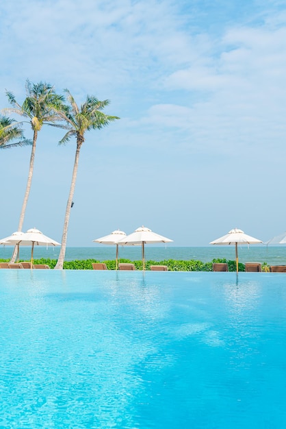 umbrella with bed pool around swimming pool with ocean sea background - holiday and vacation concept