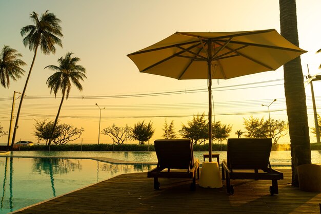 umbrella with bed pool around swimming pool with ocean sea background - holiday and vacation concept