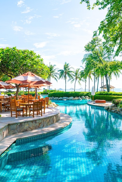 Umbrella with outdoor patio chair and table around swimming pool