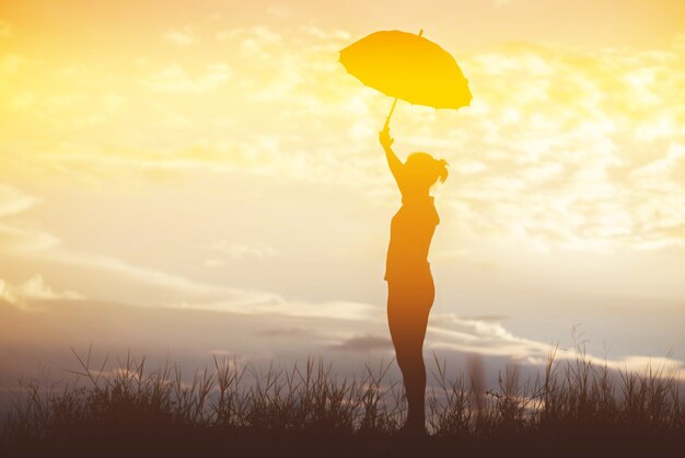 傘の女性と夕日のシルエット