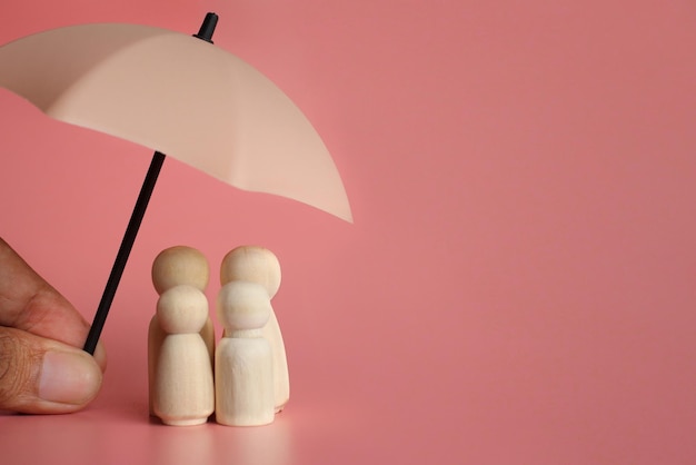 Umbrella and wooden dolls with copy space. family protection\
and insurance coverage concept.