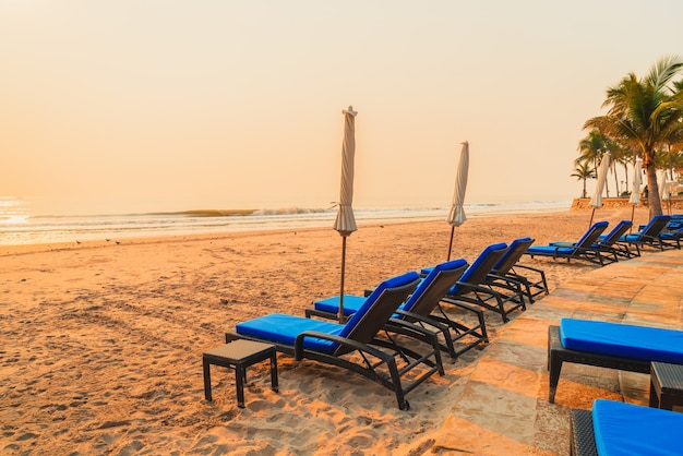 umbrellas and chairs at the beach with palm trees at sunrise