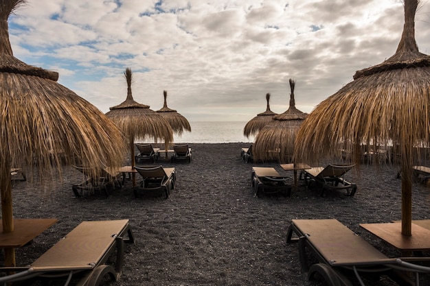 Umbrellas and seats on the beach in tenerife island. place for vacation with no one there. closed time for bad weather