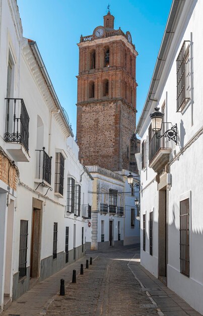 Photo una calle peatonal de casas blancas en la villa espanola de zafra con el campanario de la parroquia de la candelaria espana