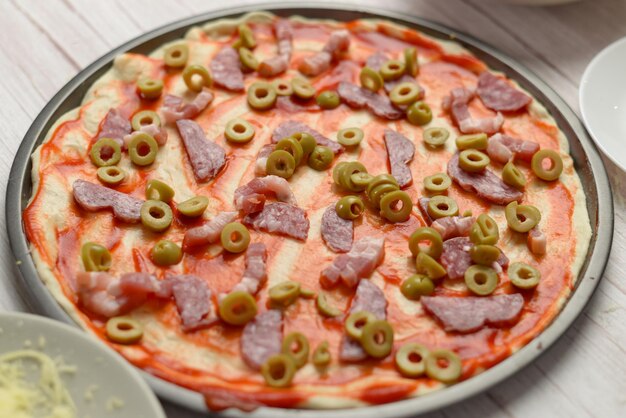 Foto pizza non cotta con condimenti su un vassoio di metallo