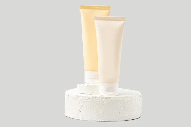 Unbranded tube of cosmetic product on white pedestal or podium on white background. skin care lotion or cream on a trendy display.Horizontal photo