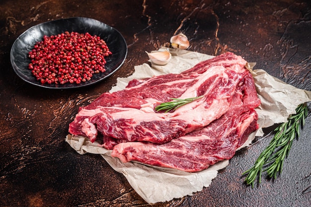 Unccoked marble black angus meat Steak on kitchen table beef chuck roll steak Dark background Top view