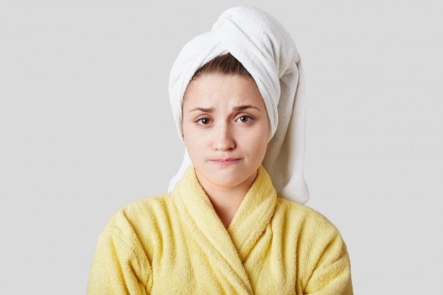 Uncertain beautiful female model wears towel and bathrobe