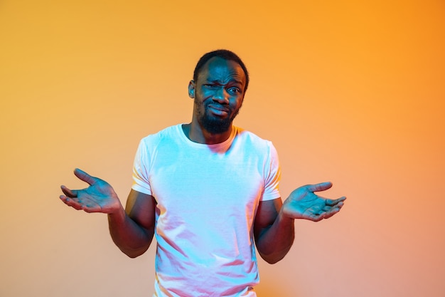 Неуверенный, чувствует себя виноватым, черт возьми. современный портрет афро-американского мужчины на градиентной оранжевой стене студии