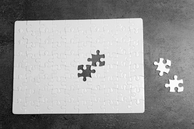 Foto puzzle bianco non collegato con pezzi su sfondo grigio