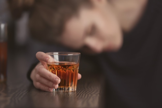 Unconscious drunk woman with glass of drink in bar, closeup. Alcoholism problem