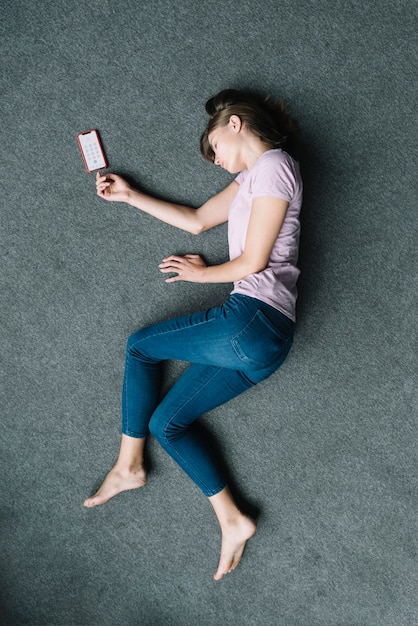 Unconscious woman lying on carpet near mobile phone