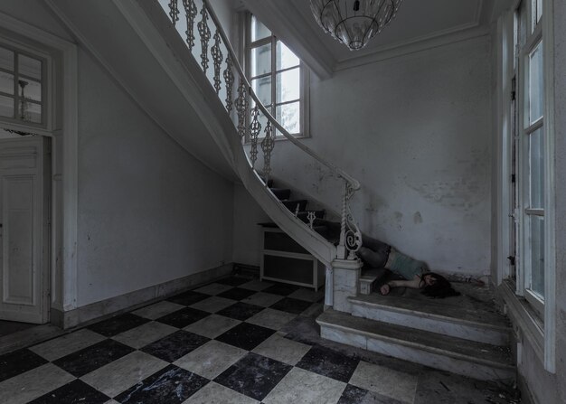 Photo unconscious woman lying on staircase in abandoned home