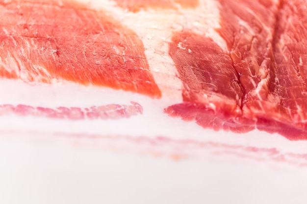 Uncooked bacon strips on a white background.