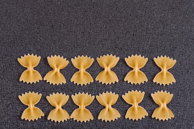 Uncooked Bow Tie Pasta on grey background.