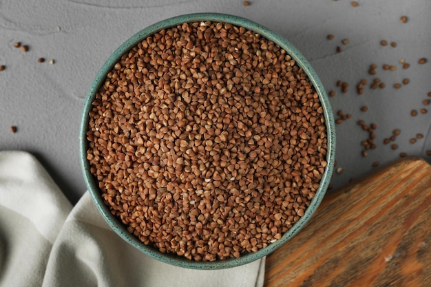 Uncooked buckwheat in bowl on table flat lay
