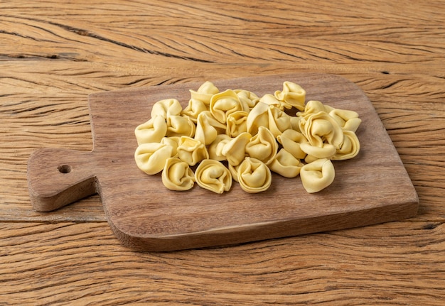 Uncooked cappelletti or tortellini on a board over wooden table