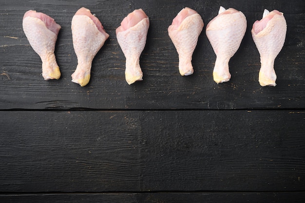 Uncooked Chicken Thigh or legs, drumsticks set, on black wooden table, top view flat lay, with copy space for text