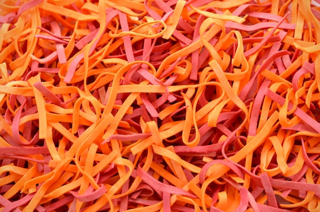 Uncooked colorful tagliolini pasta with beet extract and chili pepper closeup