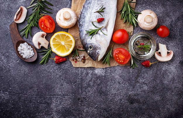 Uncooked dorado fish with rosemary and vegetables