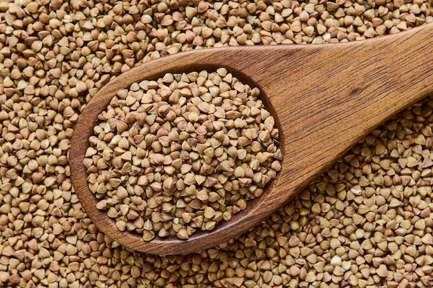 Uncooked dried buckwheat in a wooden spoon