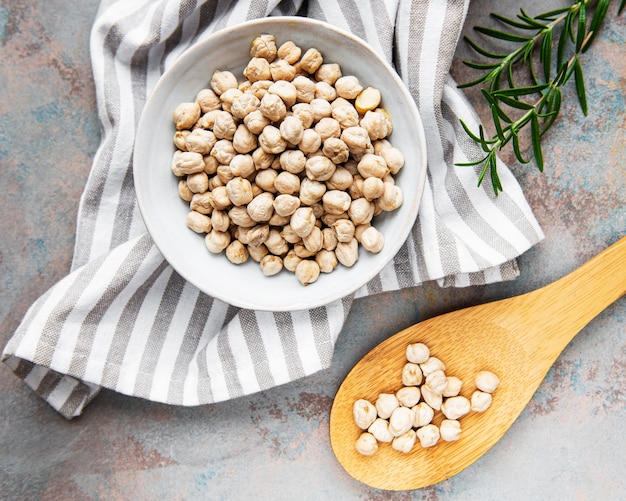 Uncooked dried chickpeas in bowl on a grey concrete background