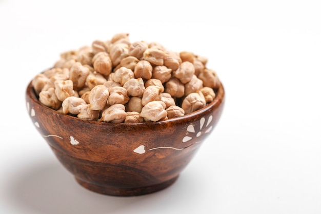 Uncooked dried chickpeas in wooden bowl