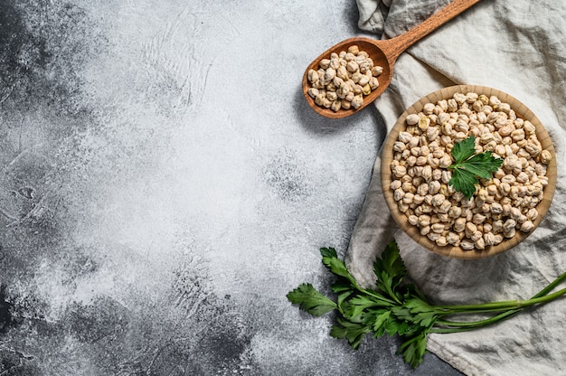 Uncooked dried chickpeas in wooden bowl.