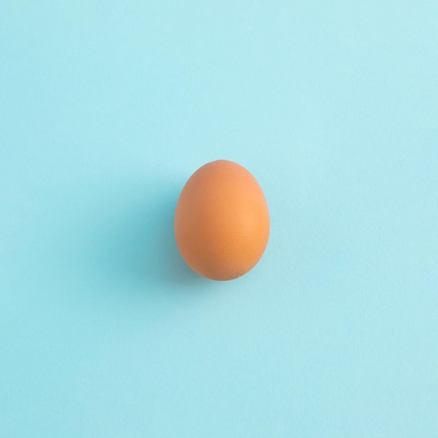 Фото Сырое яйцо на пастельно-голубом фоне минимальная концепция еды с копировальным пространством вид сверху на плоскую планировку