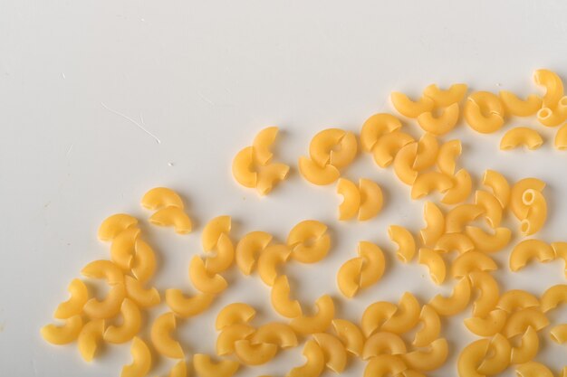 uncooked elbow macaroni on a white background