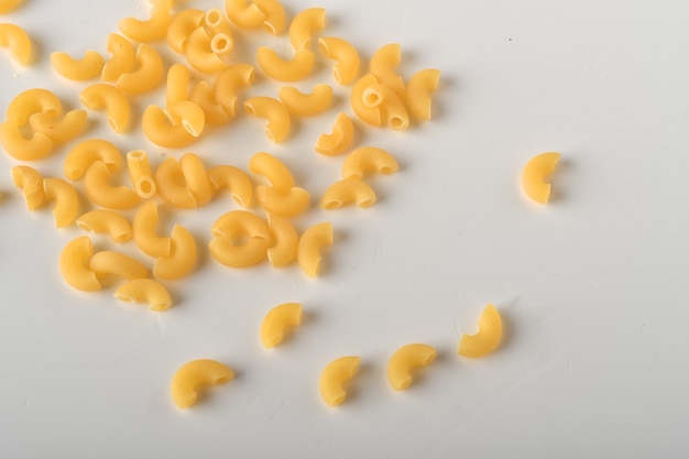 uncooked elbow macaroni on a white background