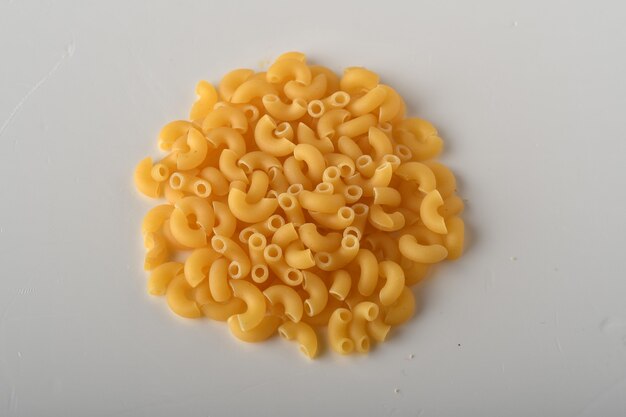 uncooked elbow macaroni on a white background