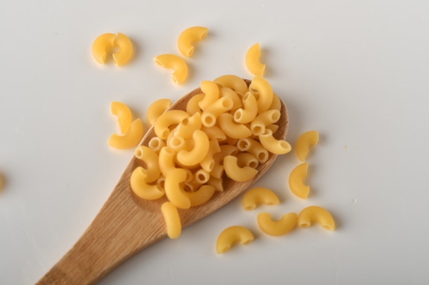 uncooked elbow macaroni on a white background